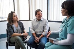 Two people sit and speak with a medical professional.